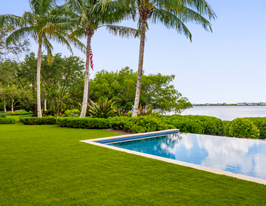a brilliant green artificial grass lawn in a tropical backyard