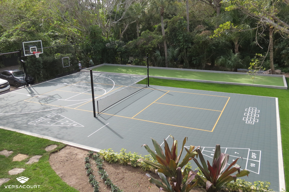 Backyard installed with a multi-sport game court featuring basketball, pickleball, volleyball, shuffleboard, and hopscotch