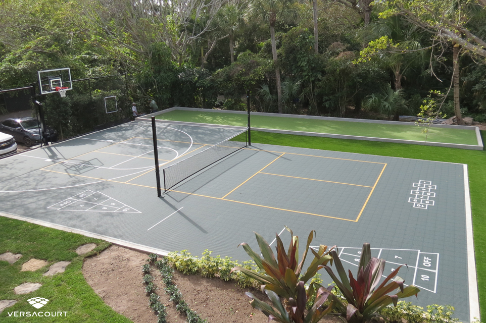 Backyard installed with a multi-sport game court featuring basketball, pickleball, volleyball, shuffleboard, and hopscotch