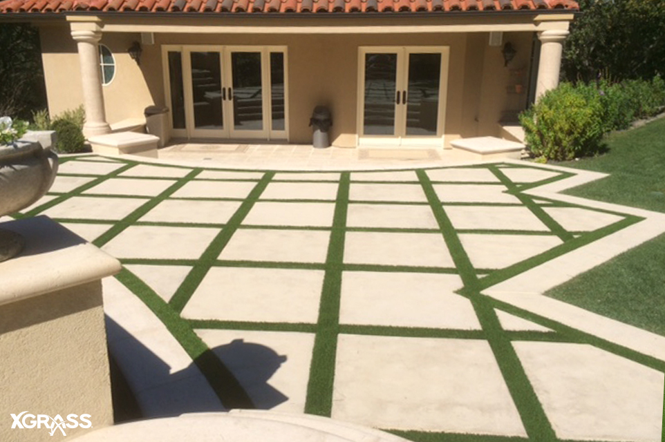 Artificial turf strips installed on paver patios in the backyard