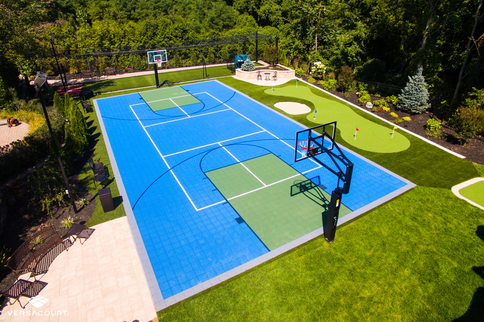 Backyard with a multi sport game court, a batting cage, and putting green