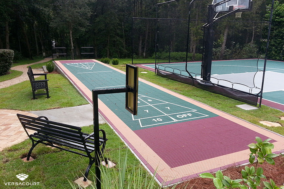 Backyard installed with a shuffleboard court, half-court basketball court, and ball rebounder